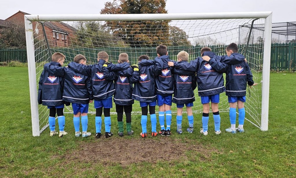 Team standing in goal with the back of their jackets showing the IFL logo.